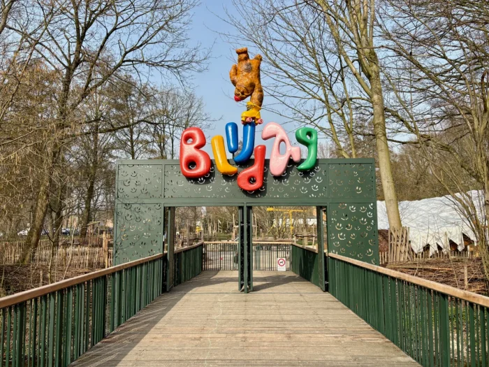 Entrance to Blijdag playground with large green gate and rainbow-colored sign with a giraffe on top
