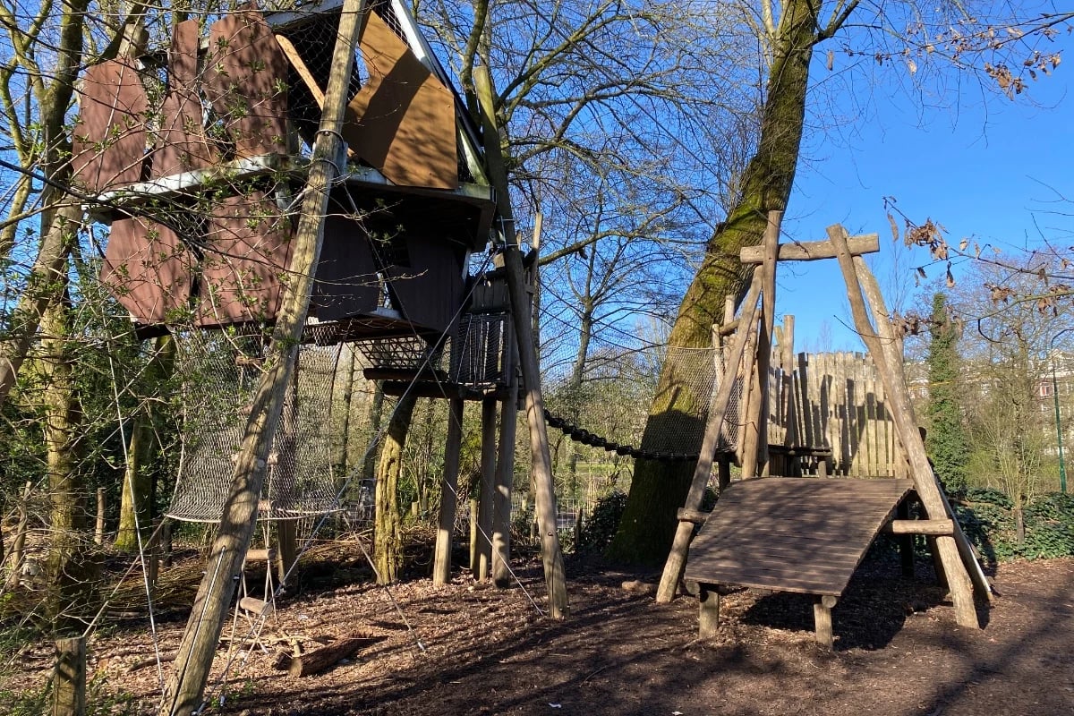 Wooden playground in the forest with zipline and large treehouse