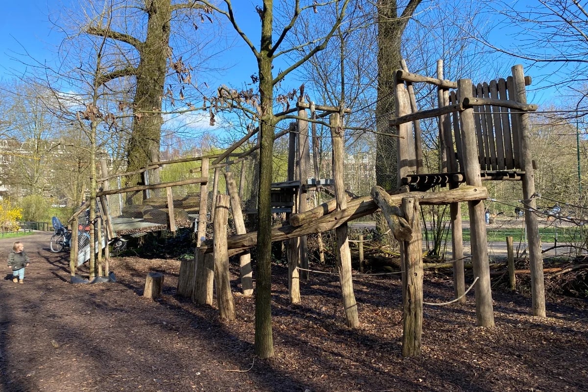 Wooden playground in the forest with climbing structure and rope obstacle course