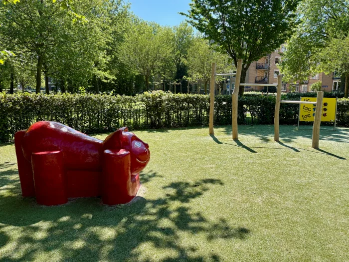 Red cat sculpture and hanging bars in sunny children's palyground