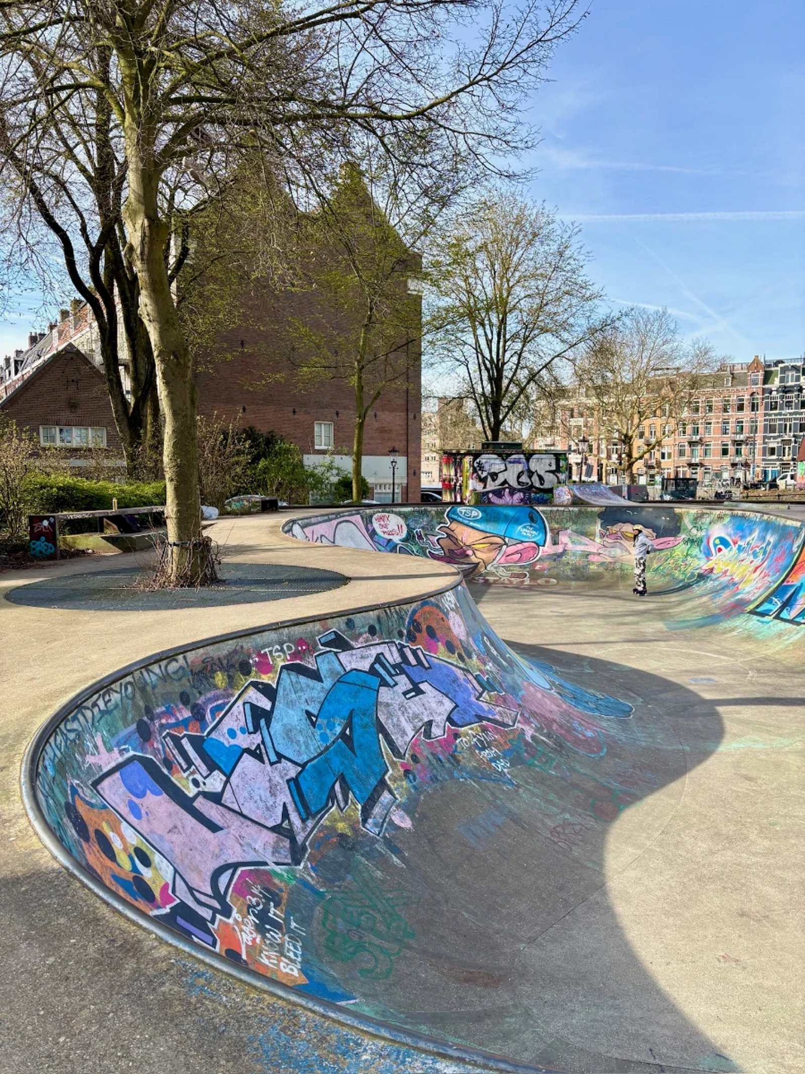 Colorful grafitti-covered skate park with bowl and smaller ramps behind