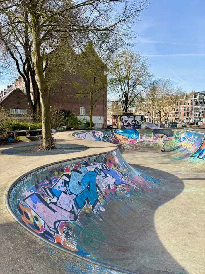 Colorful grafitti-covered skate park with bowl and smaller ramps behind