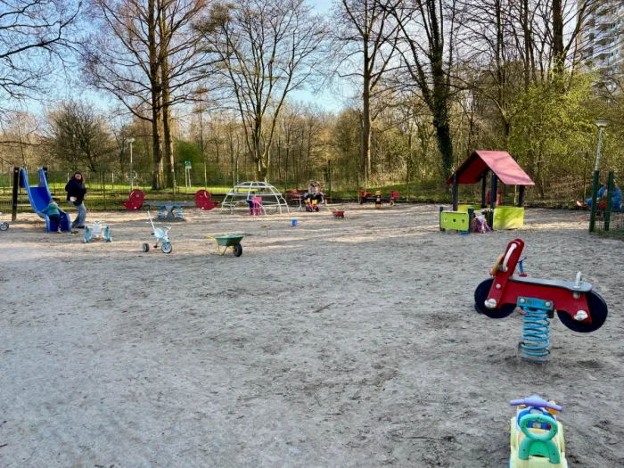 Sandy playground with blue slide, play house, and red motorcycle rocker