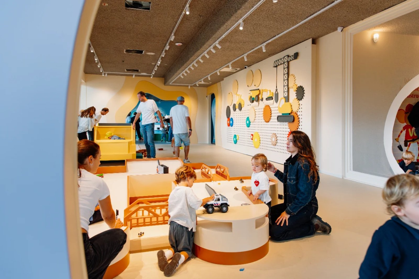 Kids and parents playing together in a bright and colorful indoor play room 