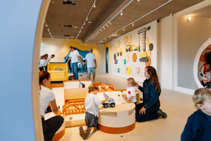 Kids and parents playing together in a bright and colorful indoor play room 