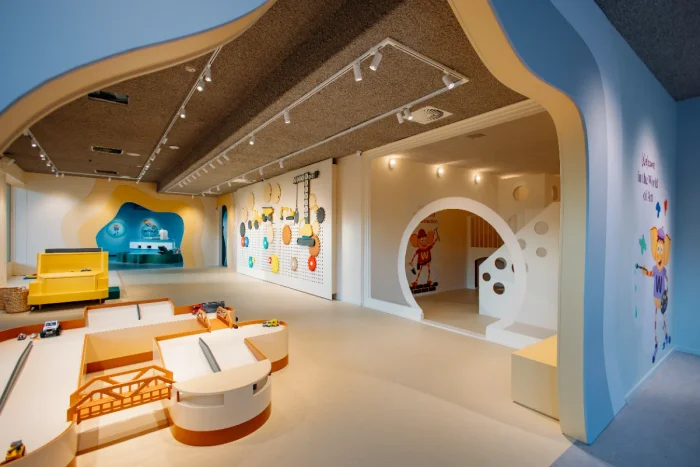 Colorful children's play center with vehicle ramp, yellow truck, and gears on the wall