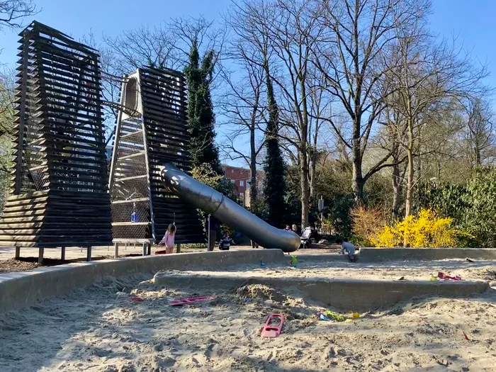 Large sand box with two wooden slat climbing towers and metal slides