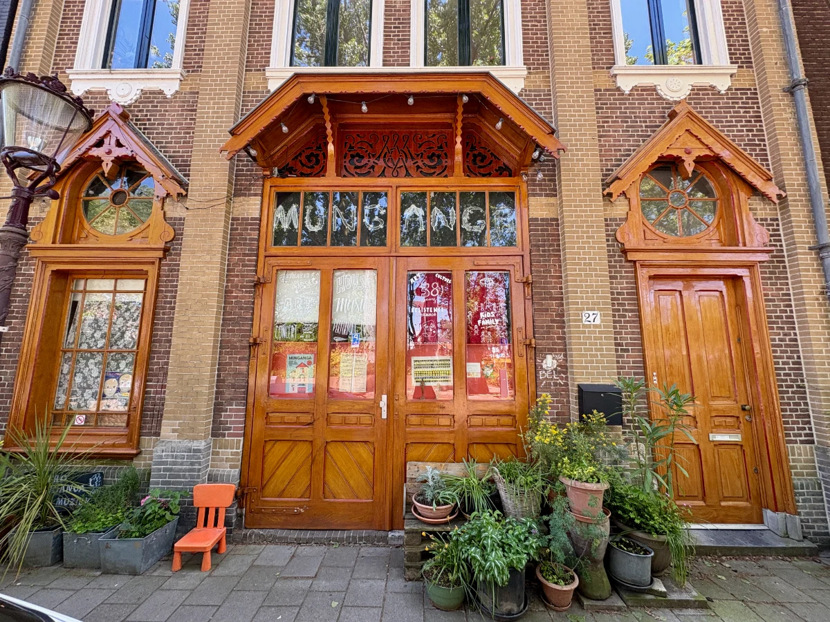 Theater entrance with ornate wooden doors and windows on brick facade with potted plants outside and signs in the window