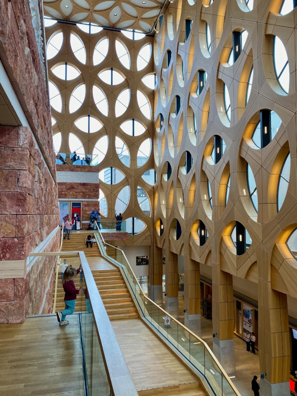 Girl looking down interior stair of Naturalis with light coming through lattice facade