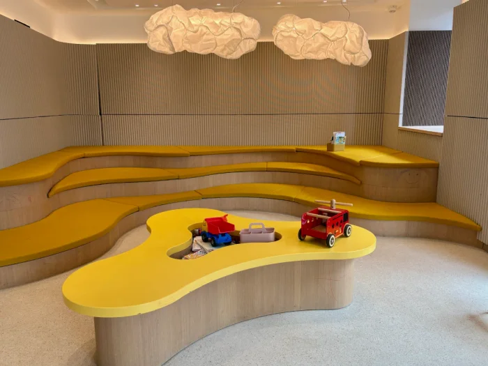 Modern play area with wavy yellow tiered seating and child-sized table with toys