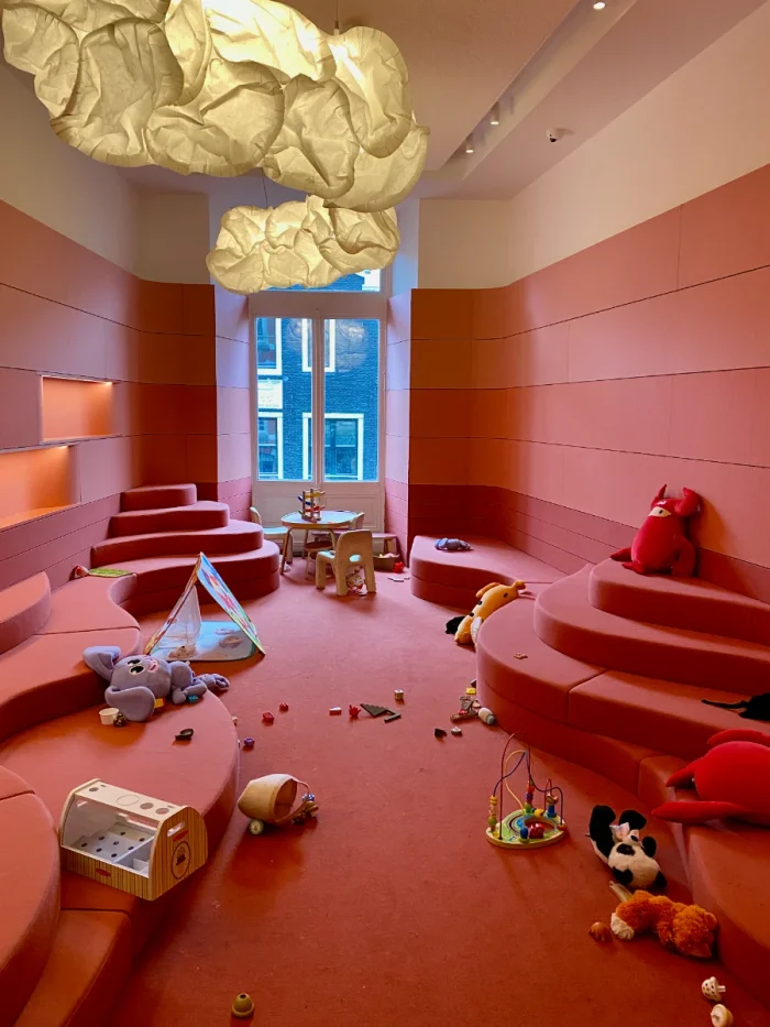 Modern red and pink soft play area with toys scattered about and cloud-shaped light above