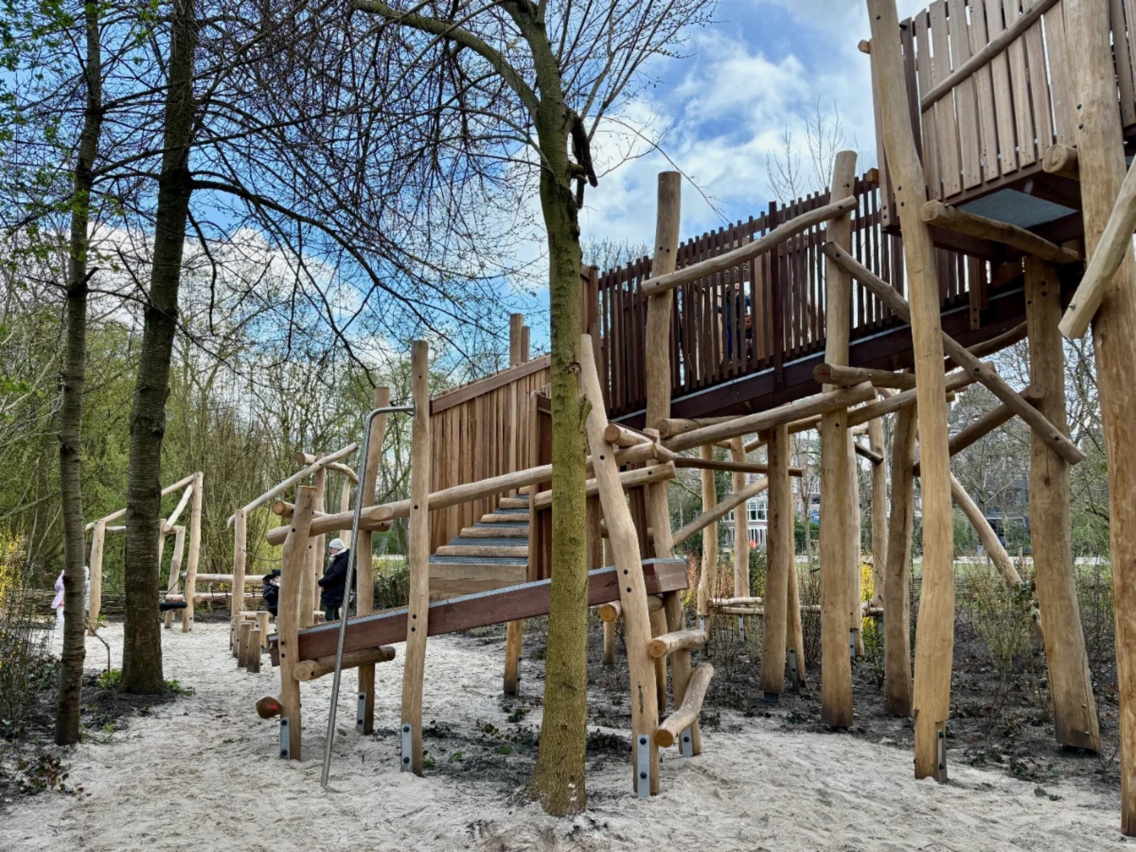 Large wooden climbing structure with ramps leading up to an elevated walkway supported by logs