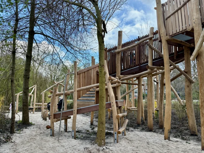 Large wooden climbing structure with ramps leading up to an elevated walkway supported by logs