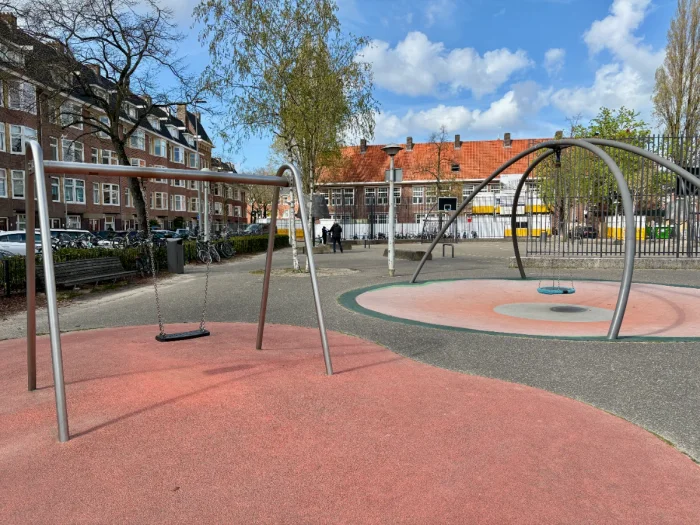 Metal frames with toddler swing and baby swing surrounded by residential buildings and trees