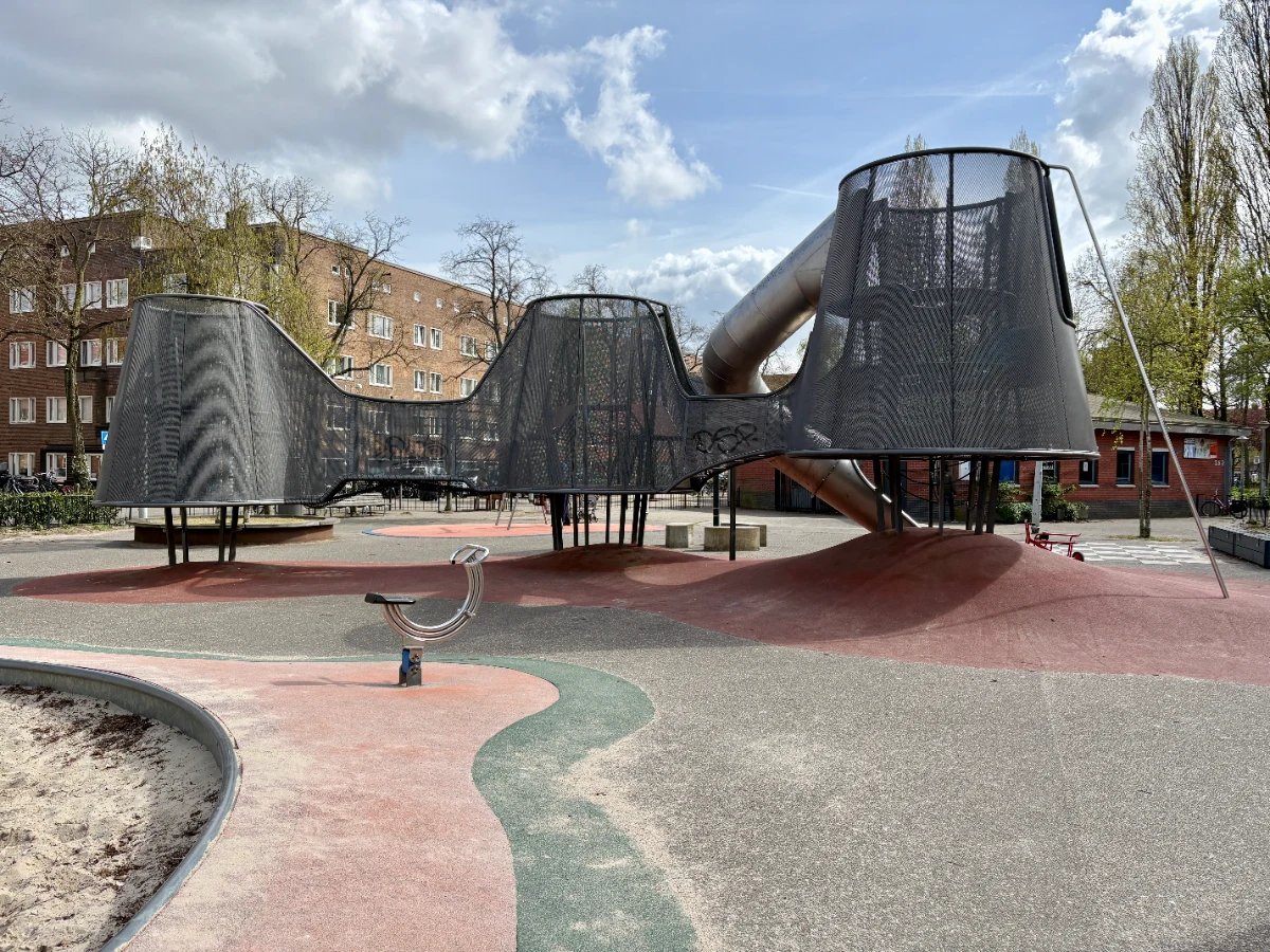 Backside of modern metal and mesh elevated play structure with metal rocker and sand box beside