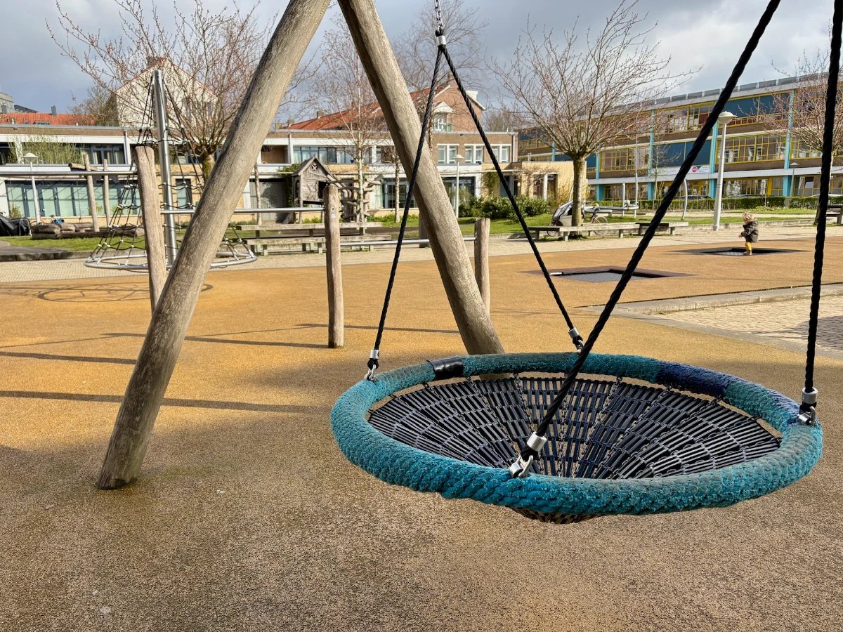 Nest swing with green rope on wooden frame at an urban playground