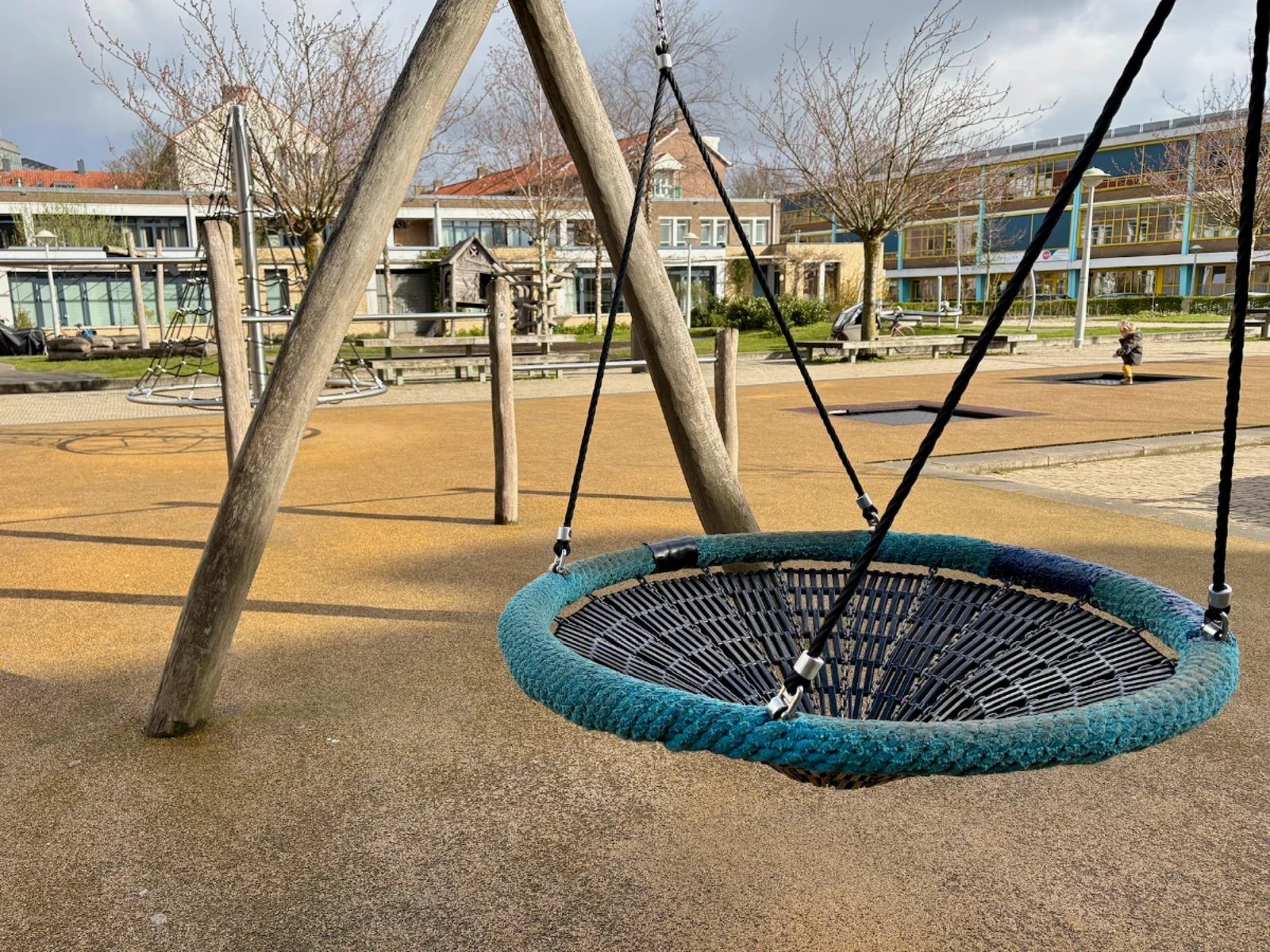 Nest swing with green rope on wooden frame at an urban playground