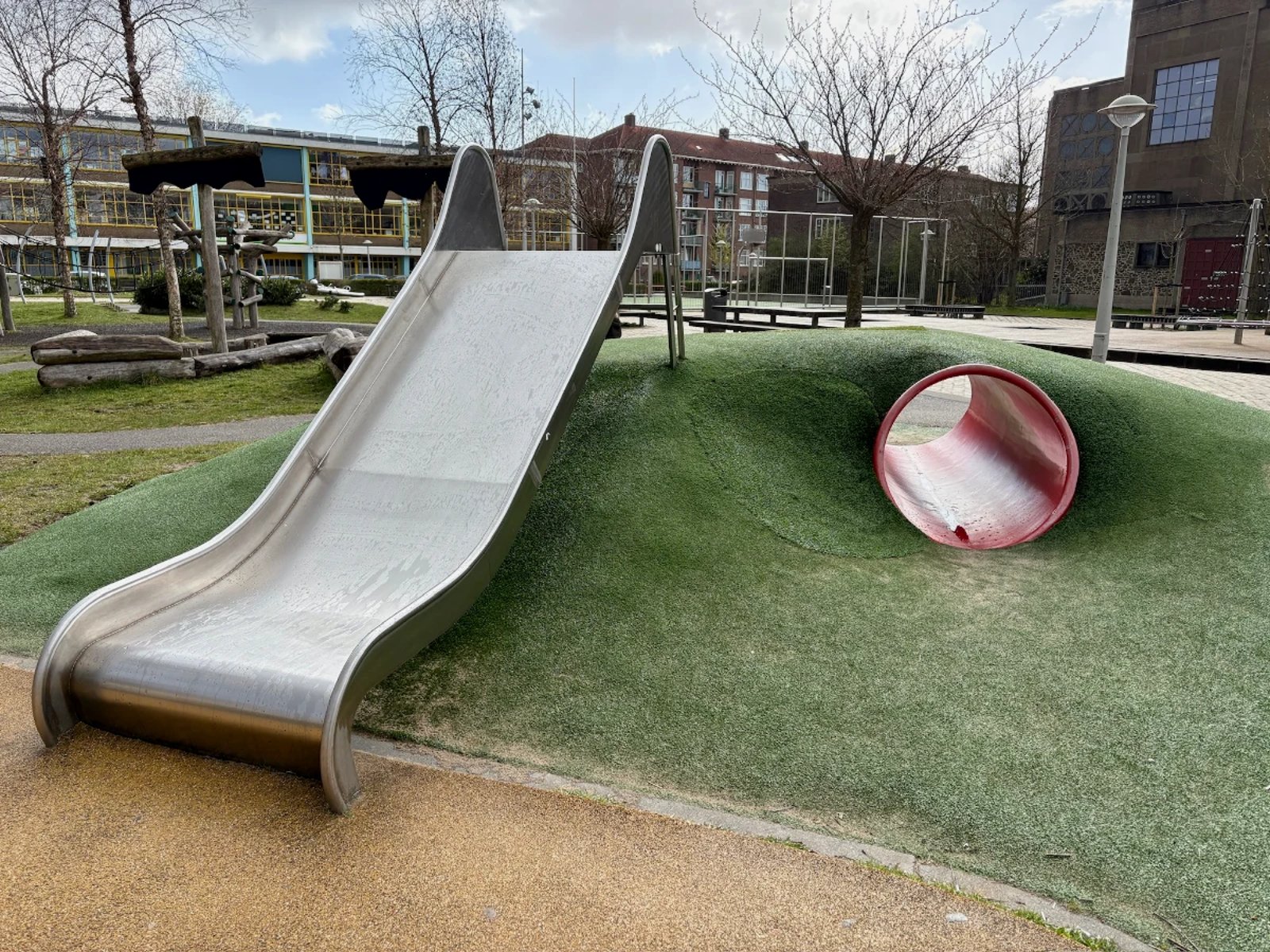 Metal slide and tunnel built into an astroturf hill