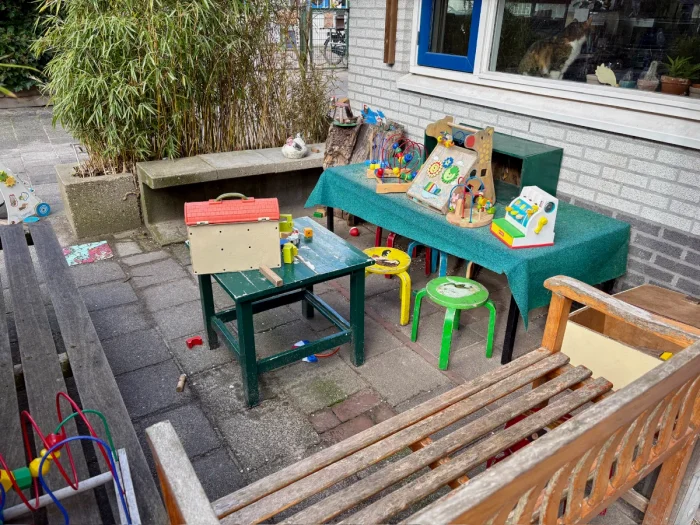 Benches arranged around a children's play area with brightly-colored toys and children's stools