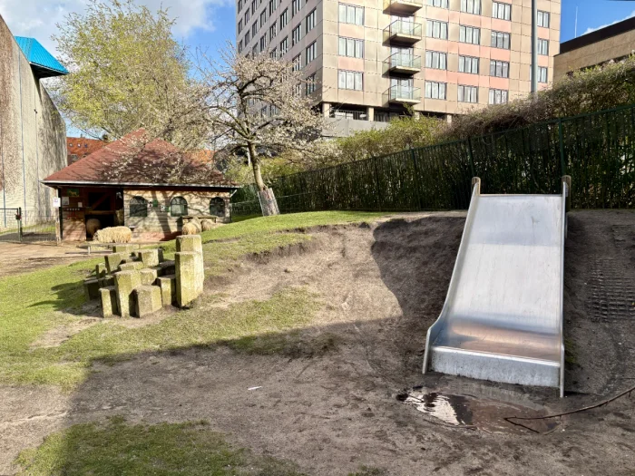 Slide and concrete climbing columns on lawn in front of barn