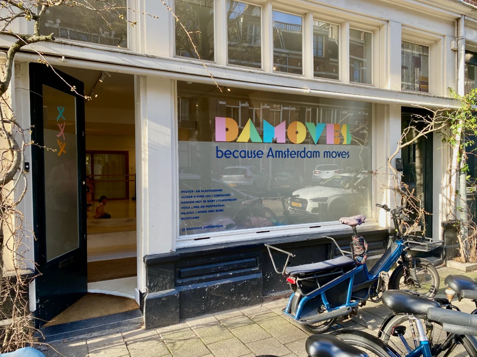 Outside of the Damoves dance studio with it's colorful logo on the windows and door ajar