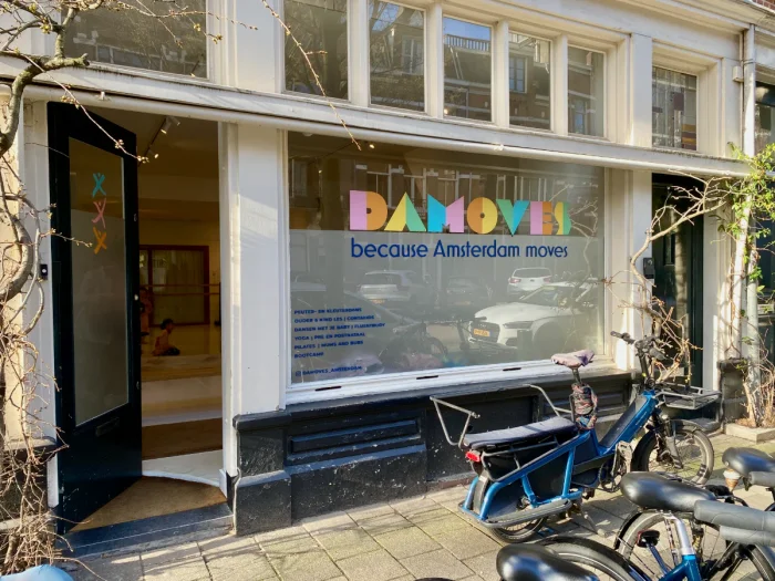 Outside of the Damoves dance studio with it's colorful logo on the windows and door ajar