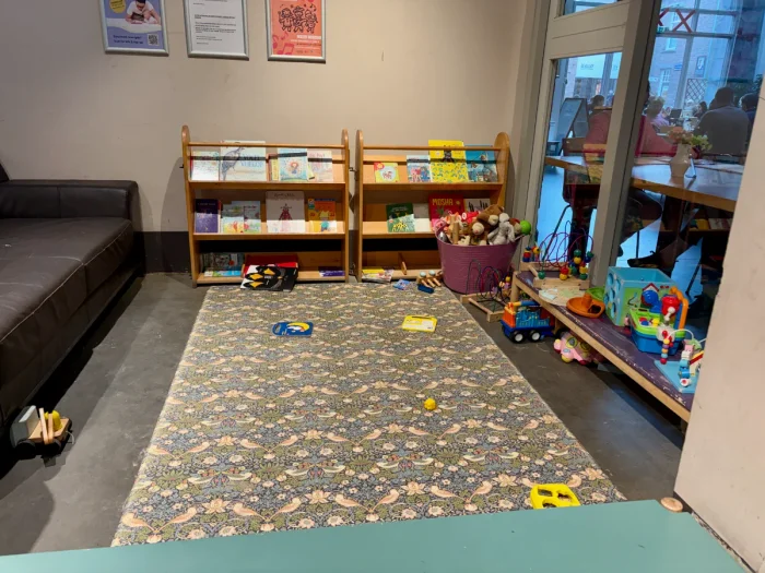 Floral play mat with shelves of books and toys for small children and couches