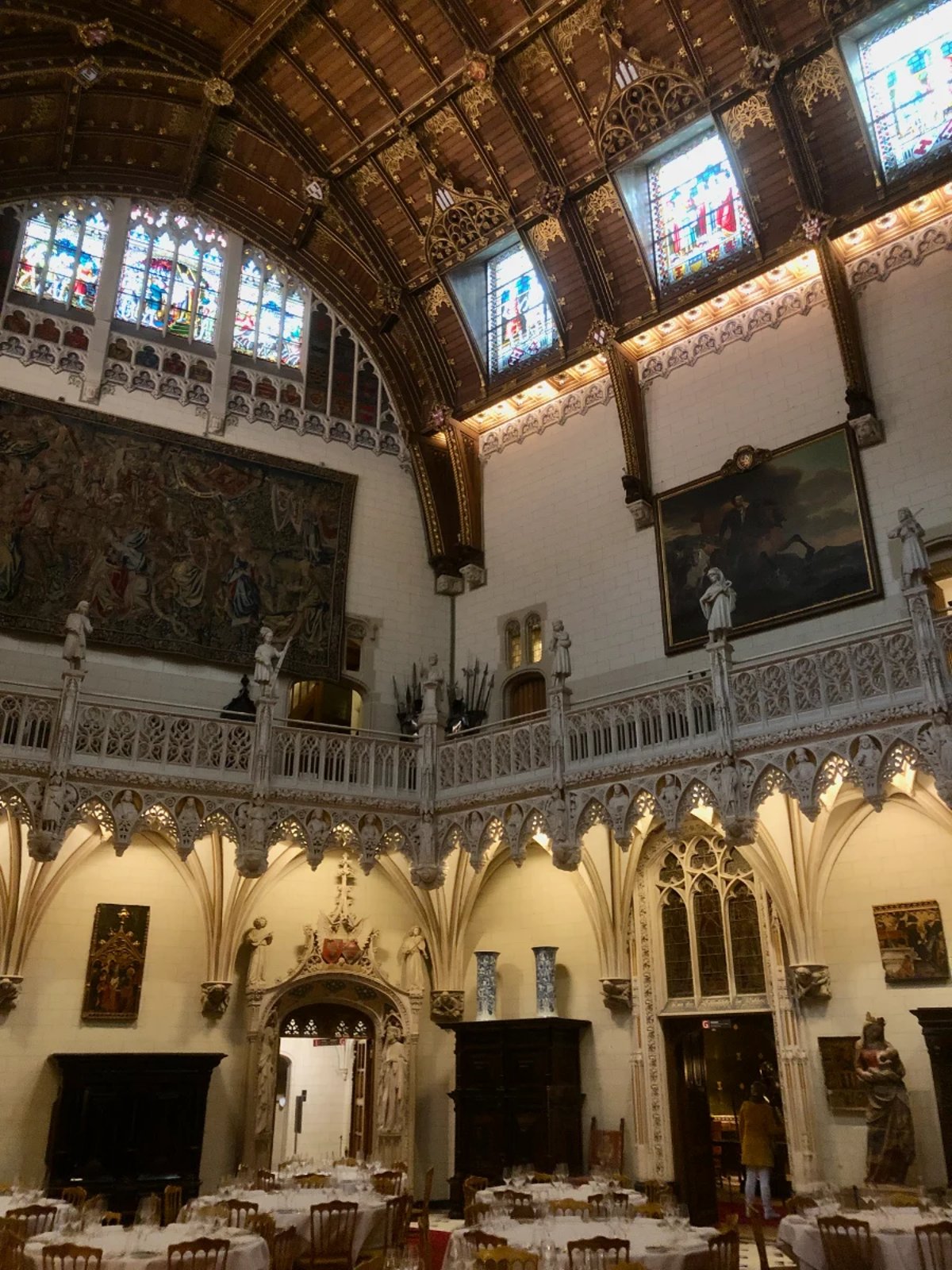 Castle interior with wooden vaulted ceiling, stained glass, and intricate stone carvings and ornate furnishings