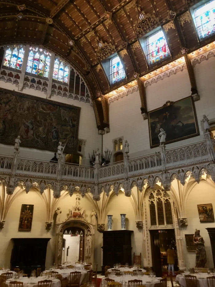 Castle interior with wooden vaulted ceiling, stained glass, and intricate stone carvings and ornate furnishings