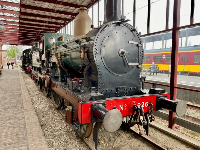 Vintage black, green, and red steam engine along a covered station platform