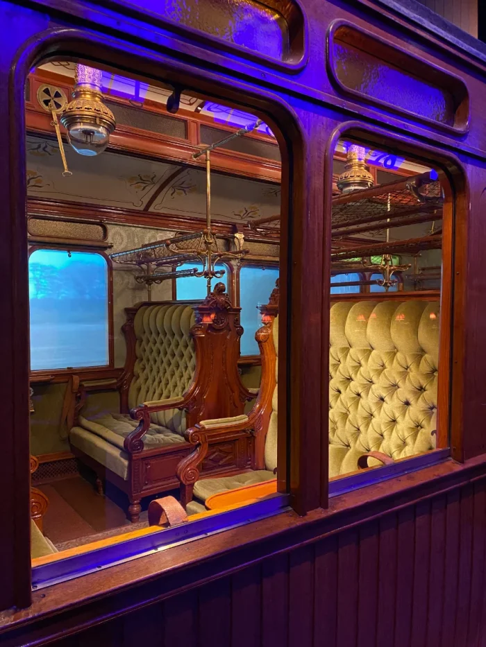 Inside of an antique rail car with plush seats and colored lighting, seen through the exterior window