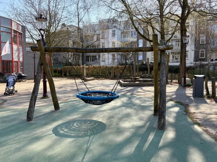 Blue nest swing on wooden frame with residential buildings behind