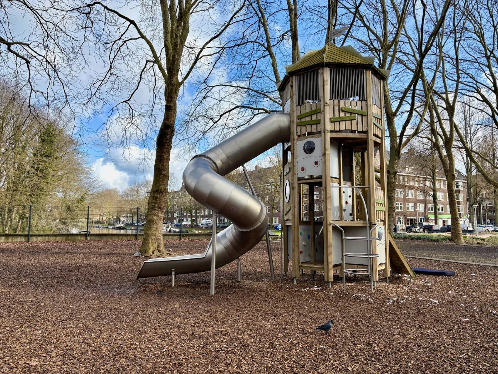 Tall wooden climbing structure with metal spiral slide