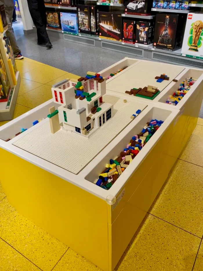 Yellow and white build table in a LEGO store with modern house built on top out of bricks