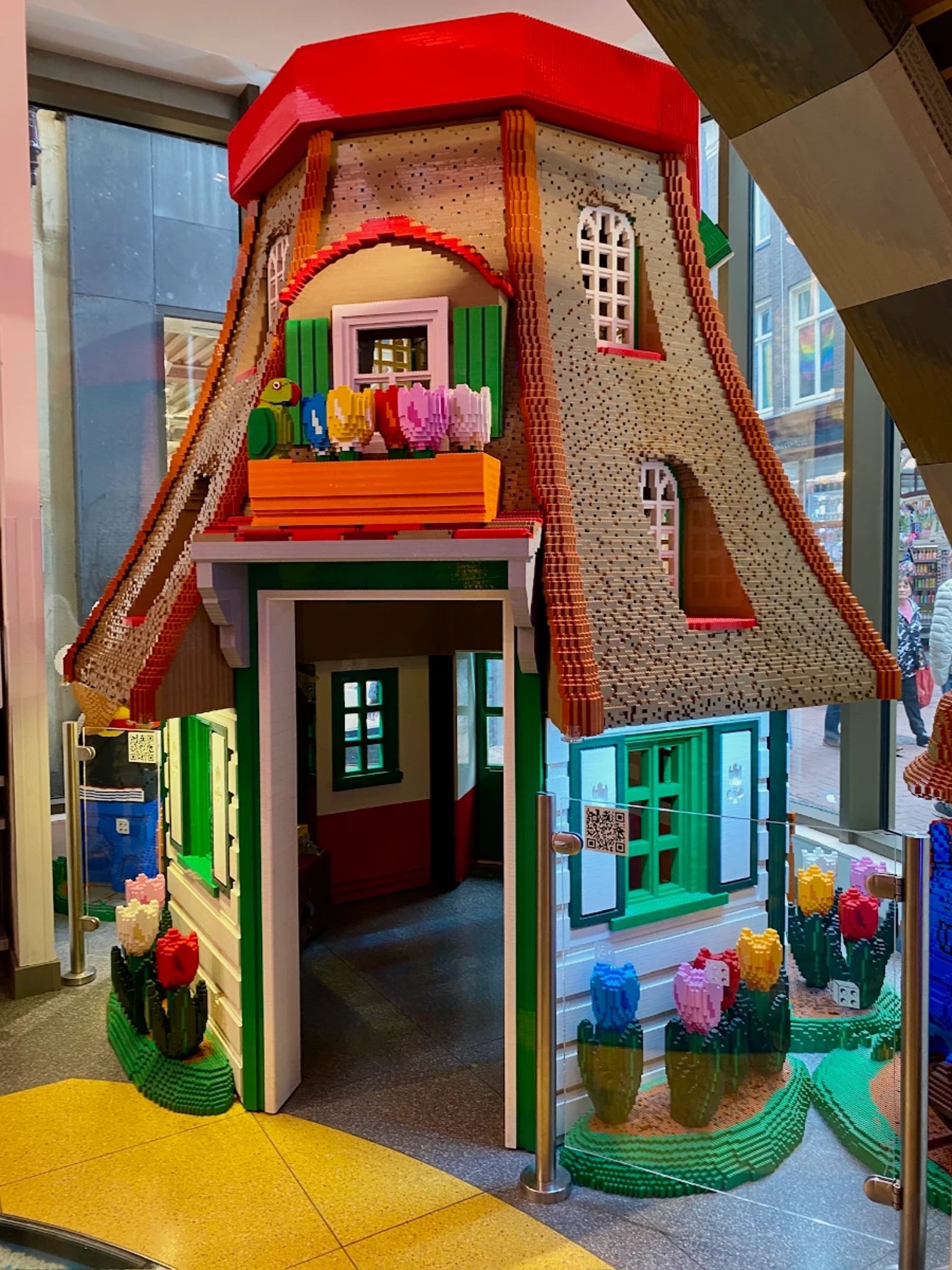 Colorful Dutch windmill build out of LEGO bricks with sloped roof and tulips in flower boxes