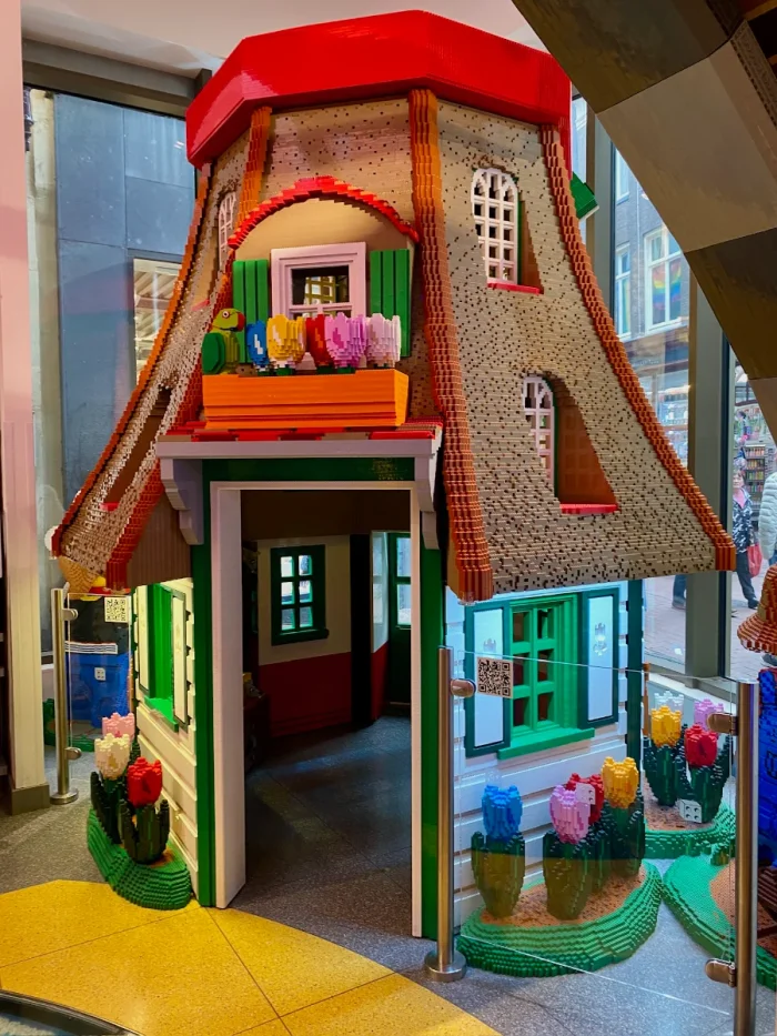 Colorful Dutch windmill build out of LEGO bricks with sloped roof and tulips in flower boxes