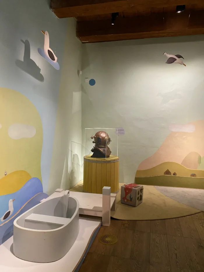 Pastel-colored, nautical-themed indoor children's play area with boat, seagulls, and diving helmet