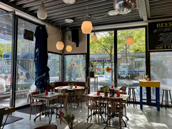 Cafe interior with wooden table and chairs and large windows looking out onto a playground
