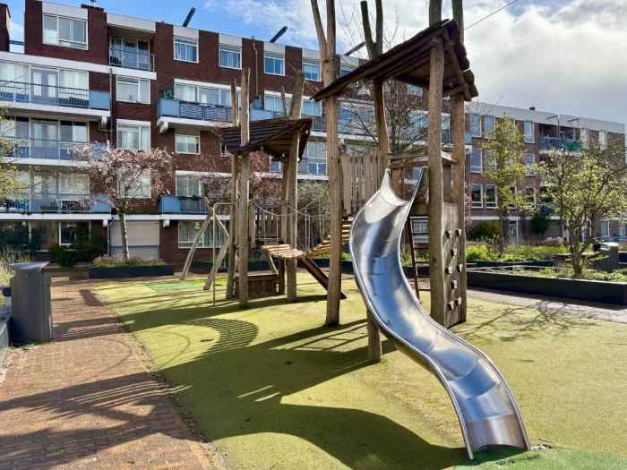 Wooden climbing structure with bridge connecting two towers and curvy metal slide