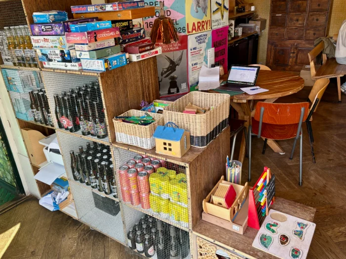 Stepping bookshelf with bottles on shelves and large toy and board game selection on top