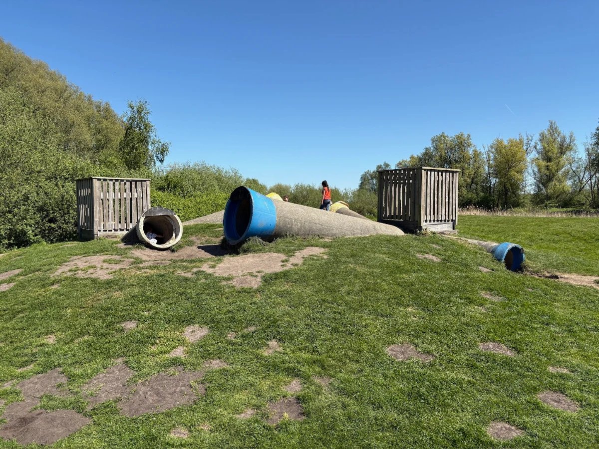 Concrete tubes jutting out of a grassy hillside with wooden boxes on top