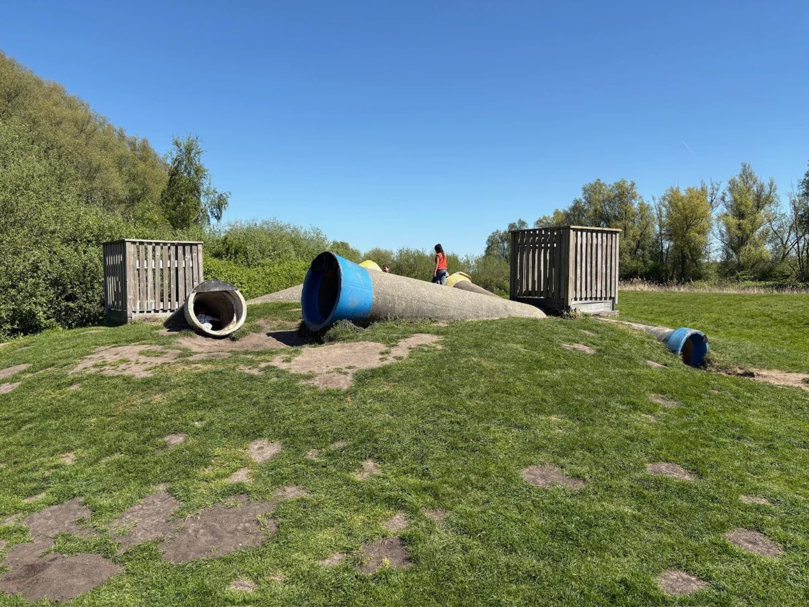 Concrete tubes jutting out of a grassy hillside with wooden boxes on top