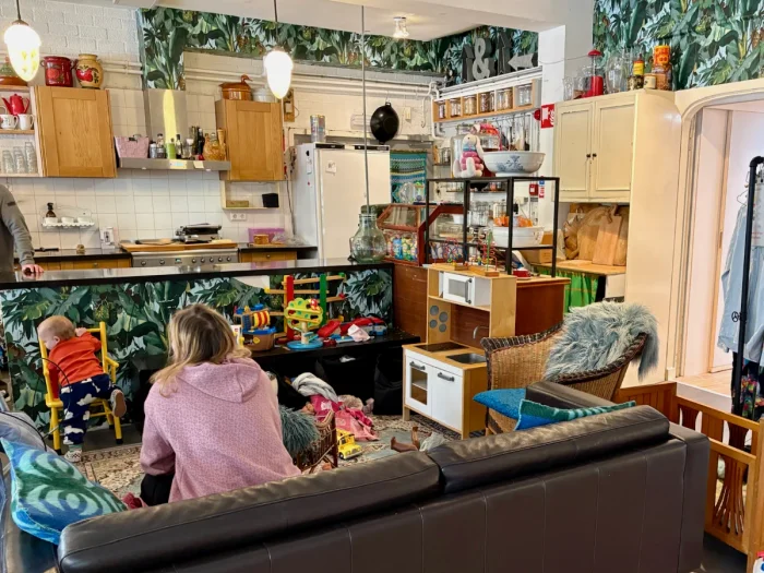 Interior of a kids cafe play area with jungle-print wallpaper, counter with kitchen behind, and lots of toys