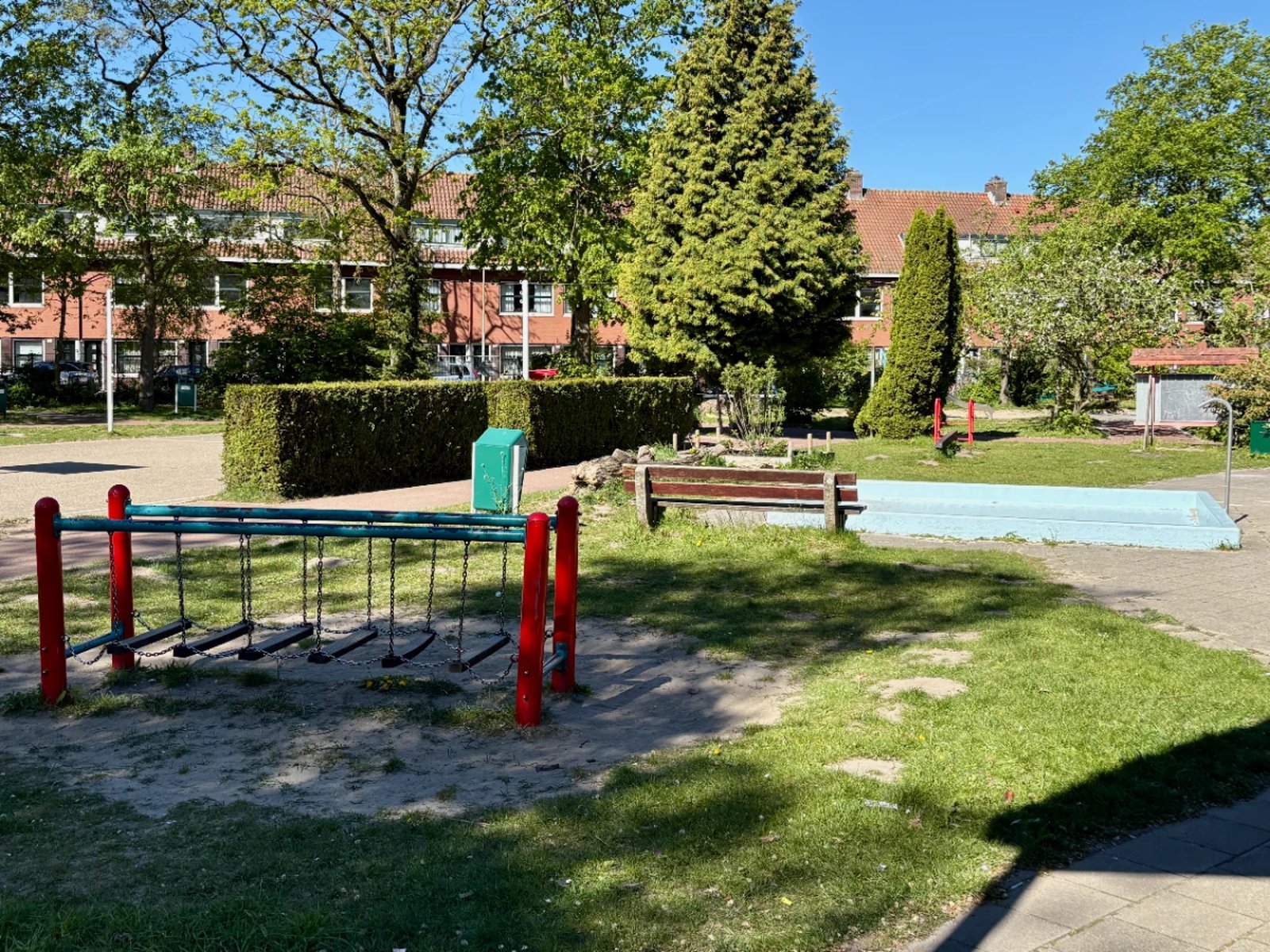 Balance bridge and empty paddling pool on sunny grassy playground