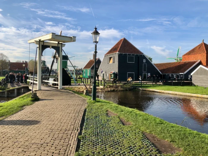 People walking through open air museum with bridge, gas lamp, historic farm buildings