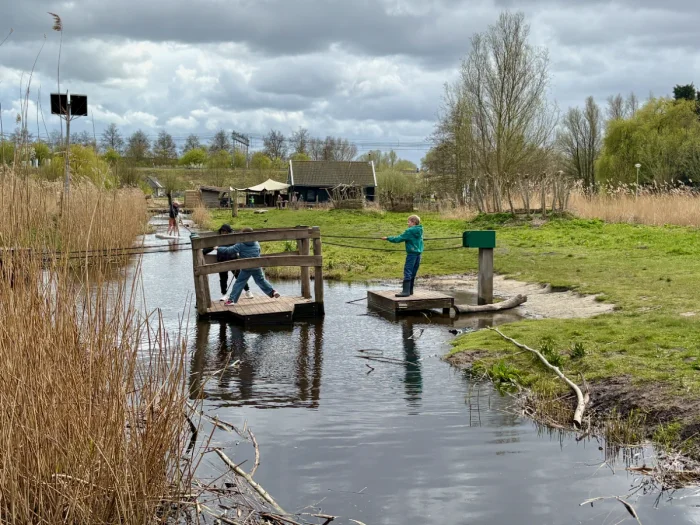 Kids operating a cable ferry to get across a canal in natural setting