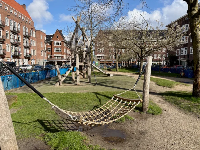 Playground on a sunny day with rope hammock in the foreground and play structure in the background