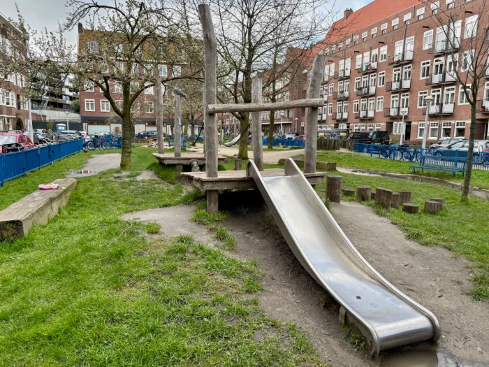 Wooden playground with slide and green grass set in a residential area
