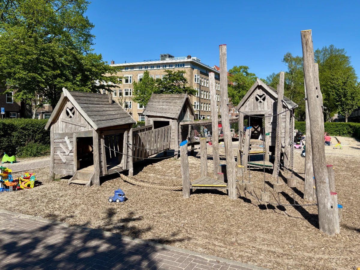 Wooden play house and obstacle course on sand with toys and trees around