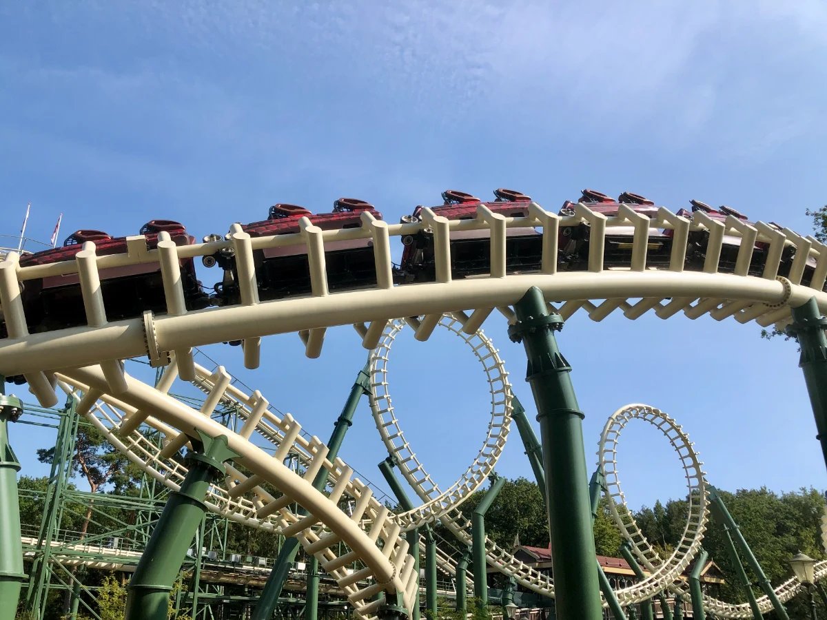 Looping roller coaster and train car passing by on a white and green track